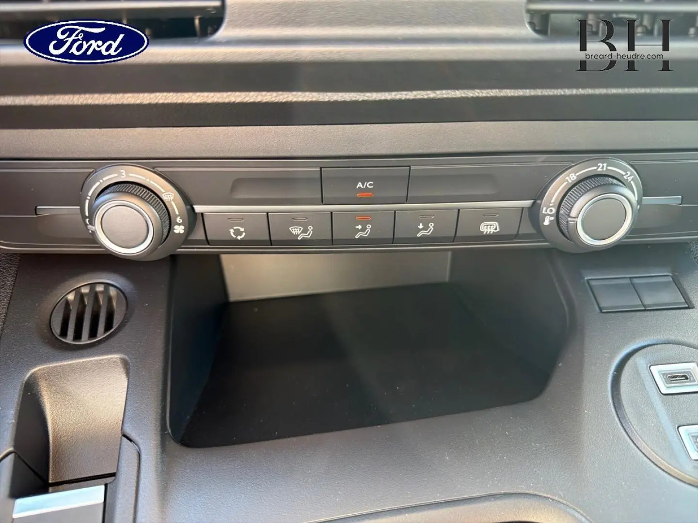 Tableau de bord en gros plan du Peugeot Partner blanc, montrant les commandes de climatisation et ventilation.