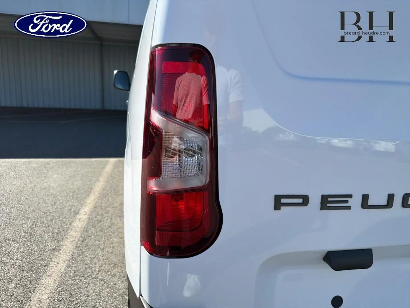 Gros plan sur le feu arrière gauche d’un Peugeot Partner blanc Icy, avec partie arrière droite du véhicule visible.