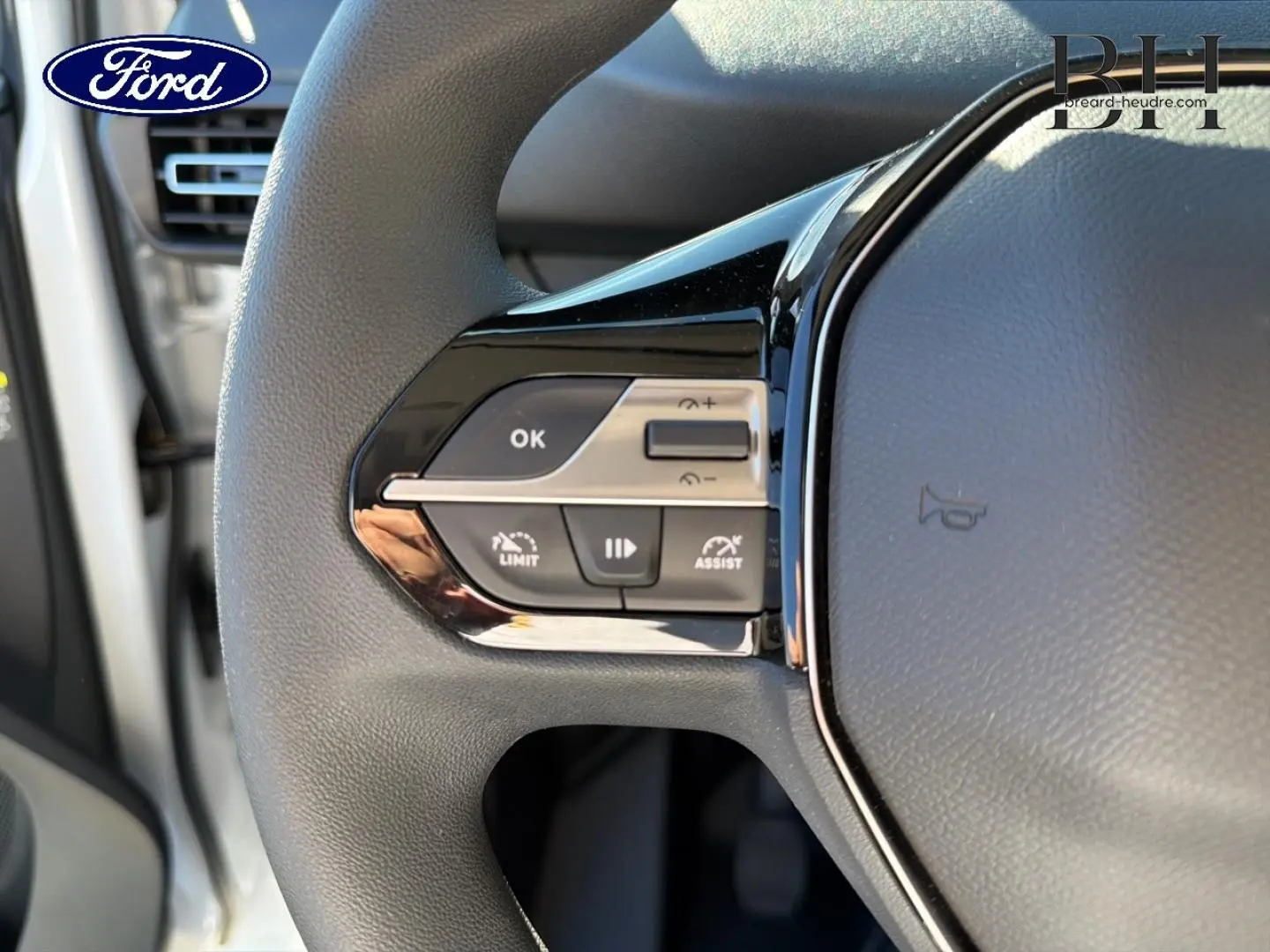 Gros plan sur le volant multifonction noir avec commandes de régulateur et limiteur de vitesse d'un véhicule Ford.