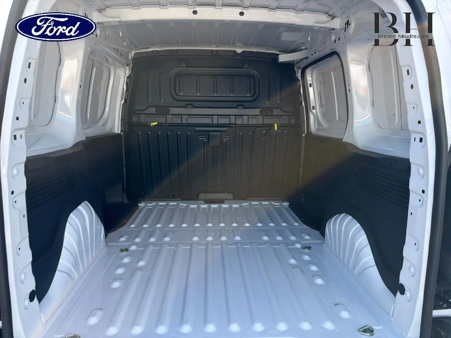 Vue intérieure arrière du coffre blanc Icy du Peugeot Partner 2025, montrant l'espace de chargement vide et la cloison pleine noire.