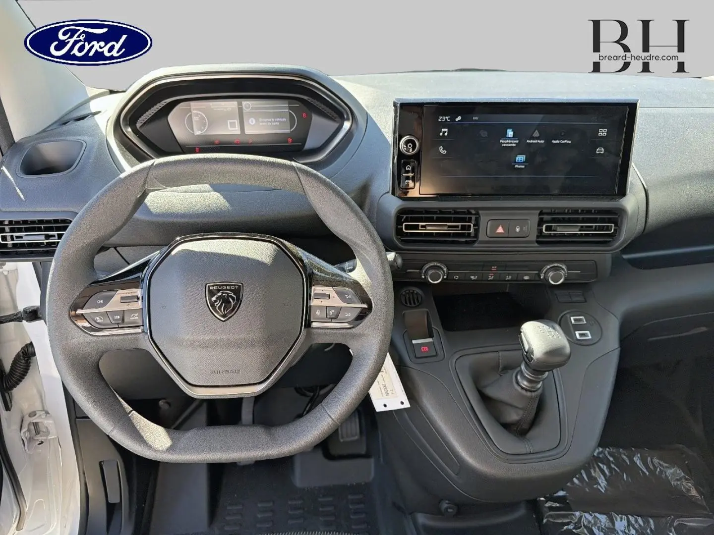 Vue intérieure frontale du tableau de bord du Peugeot Partner 2025 avec volant multifonction et écran tactile central.
