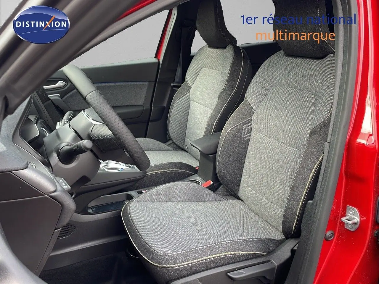 Intérieur avant du Renault Captur rouge passion 2025, sièges tissu gris avec surpiqûres contrastées et volant visible.