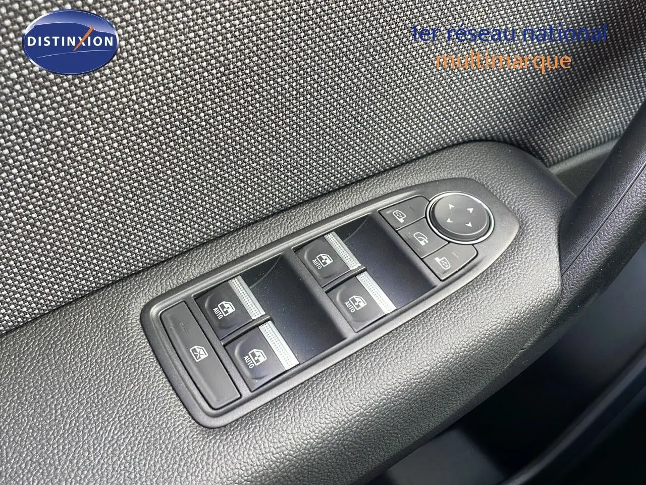 Gros plan sur les commandes des vitres électriques et réglage des rétroviseurs sur la porte intérieure d'un Renault Captur rouge 2025.