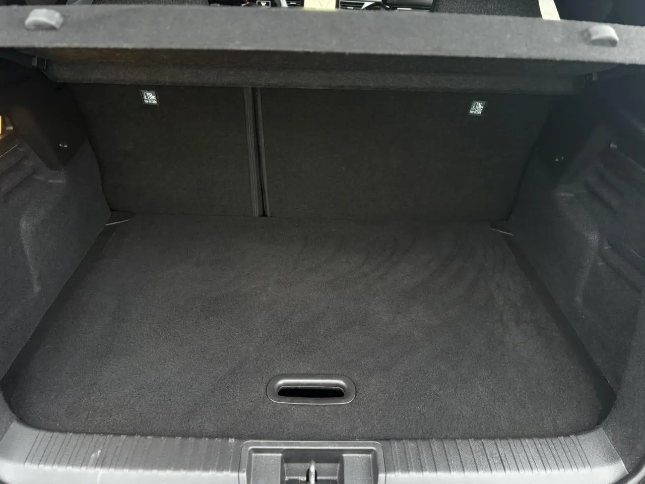 Vue intérieure du coffre spacieux et plat du Renault Captur 2025 gris Cassiopée avec finition noire.