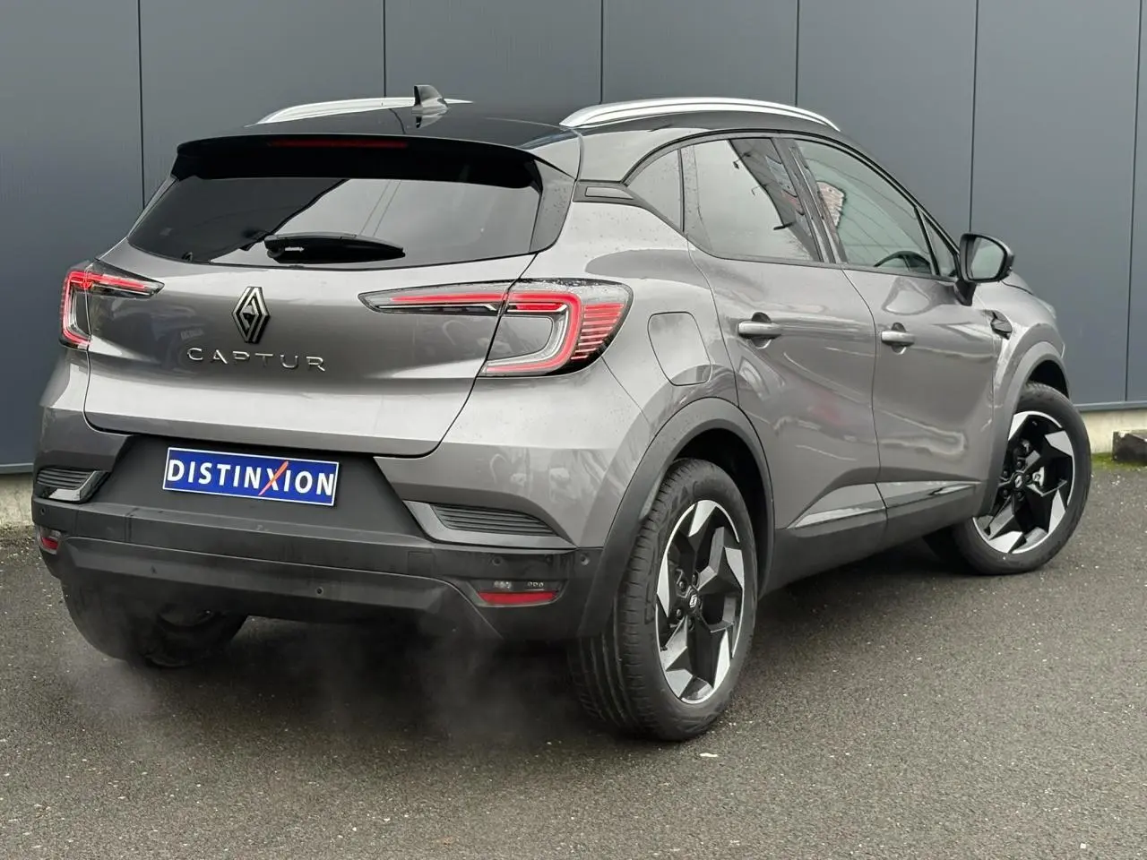 Vue 3/4 arrière droite du Renault Captur 2025 gris Cassiopée avec toit noir et jantes alu diamantées noires.