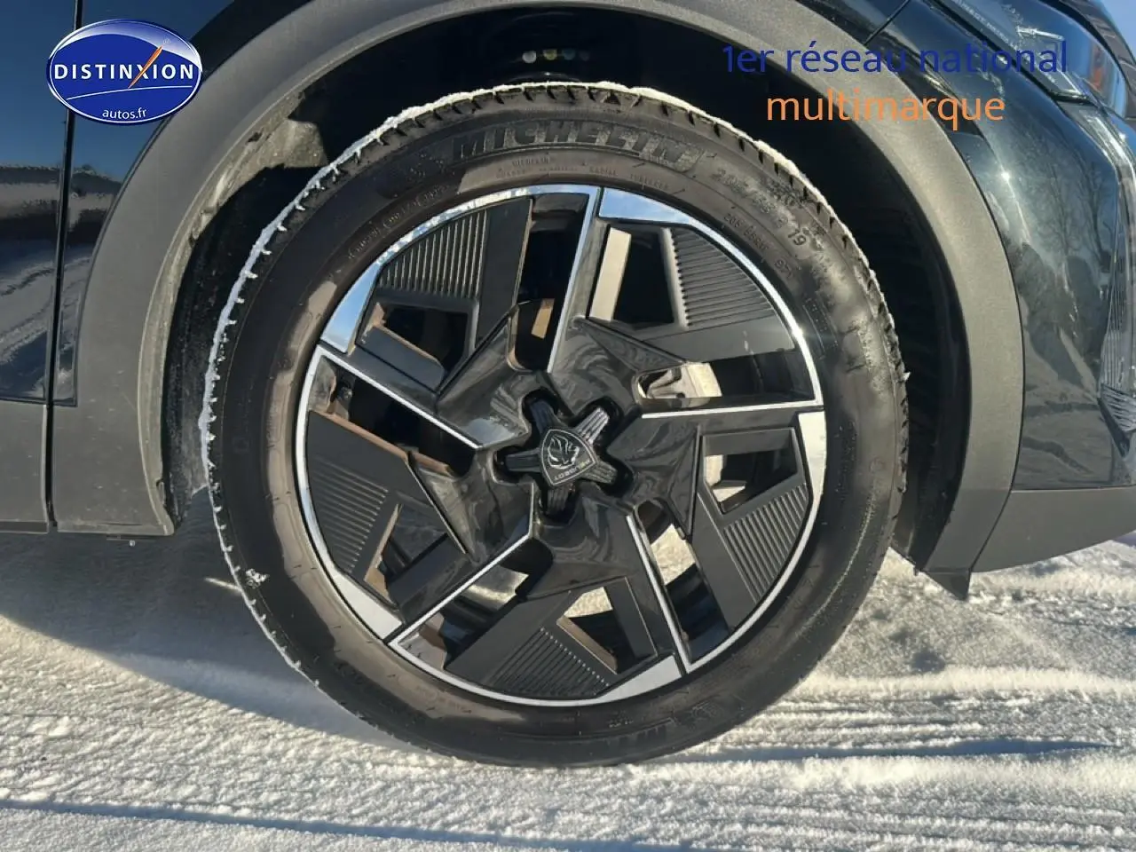 Gros plan sur la roue avant droite noire d'une Peugeot 408 Hybrid 145 GT e-dcs6 avec jante alu au design moderne.