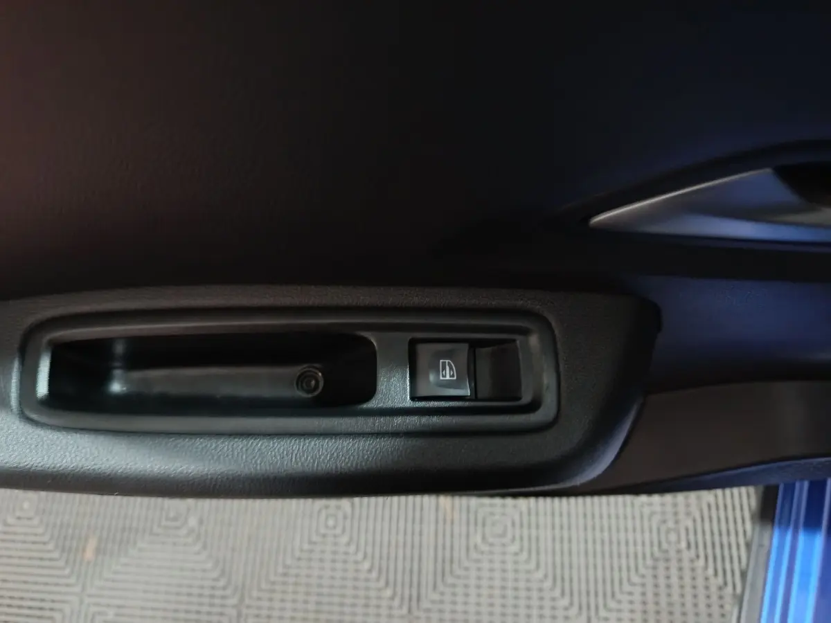 Gros plan sur le bouton de verrouillage centralisé sur la porte côté conducteur d'une Dacia Sandero bleu 2024.