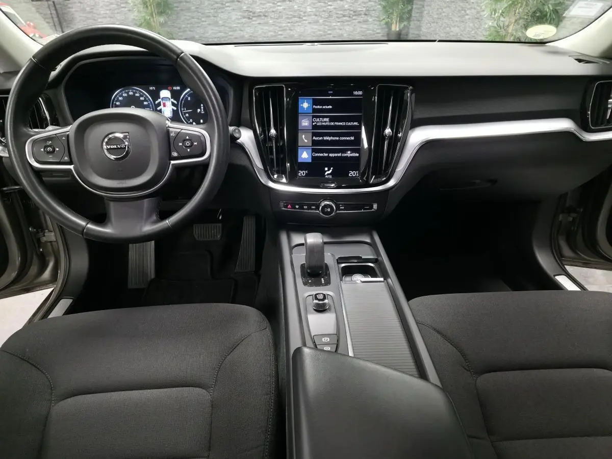 Vue intérieure avant de la Volvo V60 gris, avec tableau de bord digital et écran tactile central vertical.