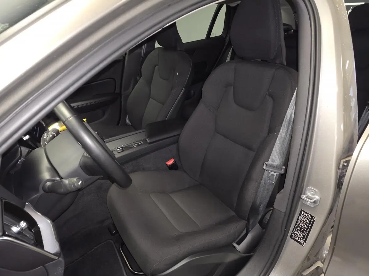 Vue intérieure côté conducteur d'une Volvo V60 gris 2021, mettant en valeur le siège textile noir et la ceinture de sécurité.