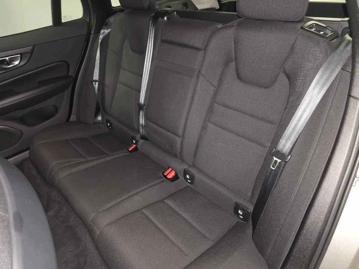 Vue intérieure sur la banquette arrière textile noire du Volvo V60 gris, avec ceintures de sécurité et ancrages Isofix visibles.