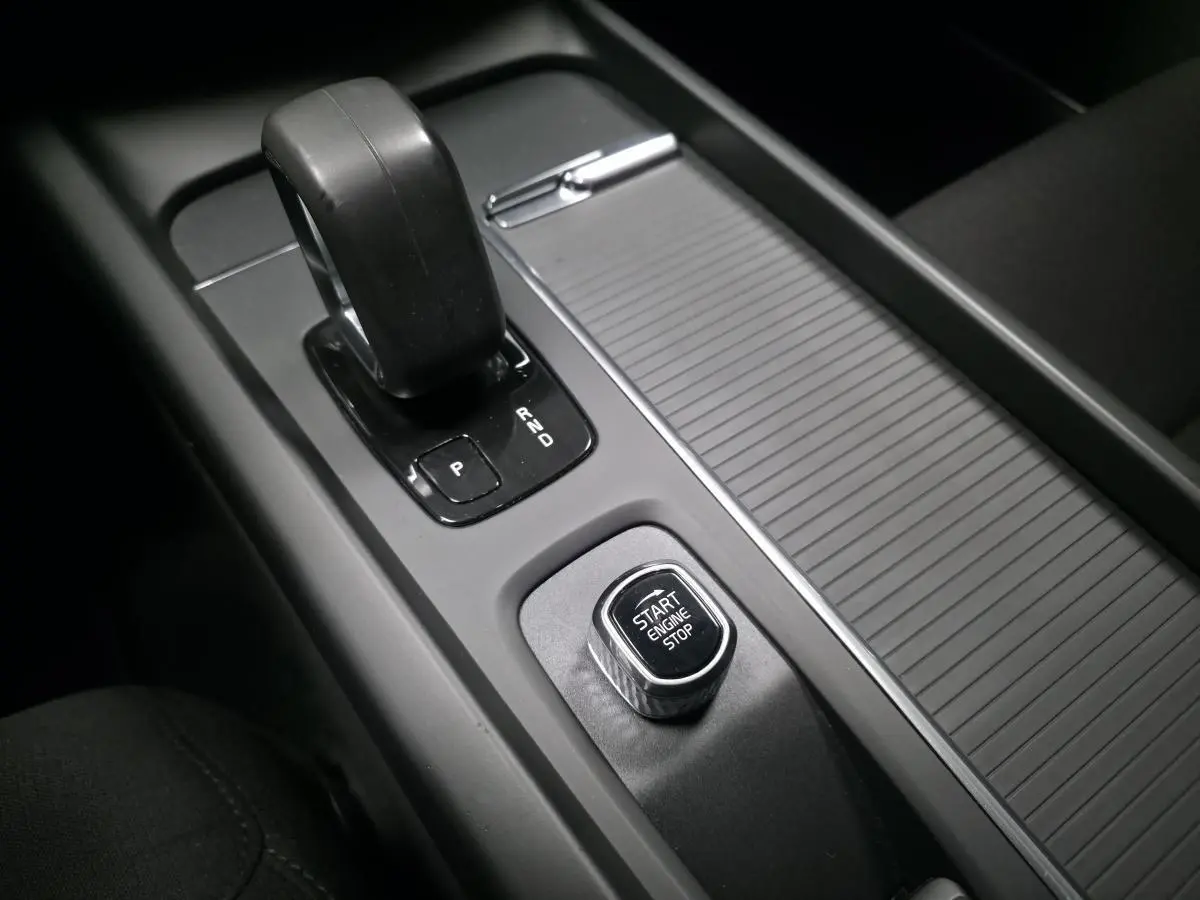 Gros plan sur la console centrale noire avec levier de vitesses automatique et bouton Start Engine Stop d'une Volvo V60.