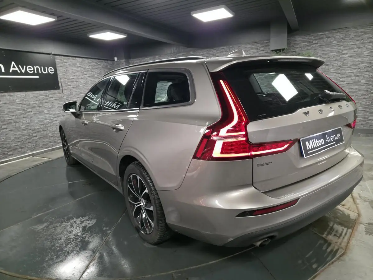 Vue 3/4 arrière droite d'un Volvo V60 gris métallisé avec feux arrière LED en forme de L et double sortie d'échappement.