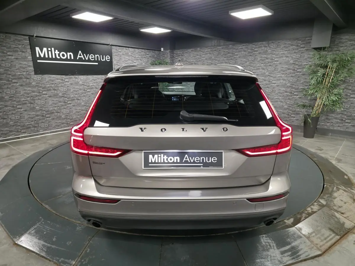 Vue arrière d'une Volvo V60 gris métallisé avec feux arrière LED en forme de L et double sortie d'échappement visible.