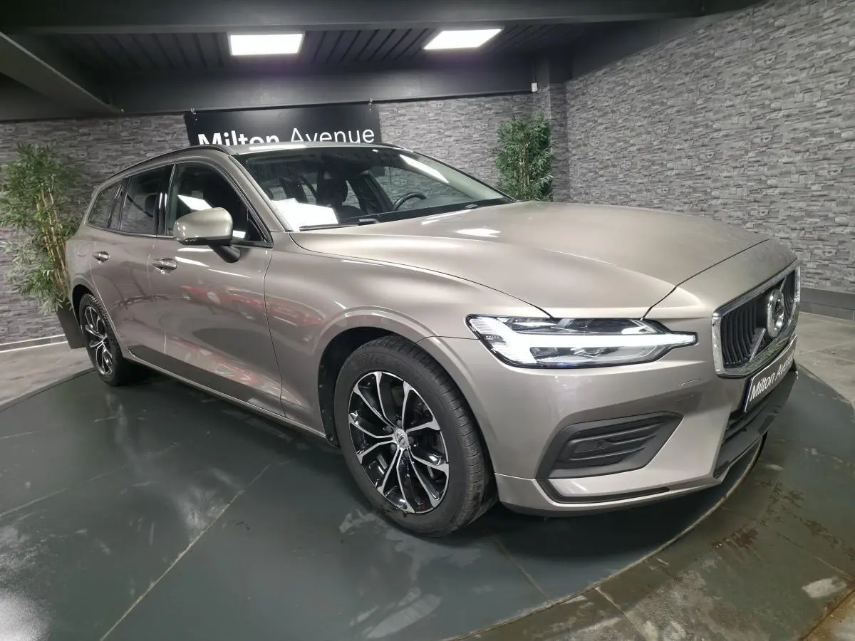 Volvo V60 B4 gris métallisé vue 3/4 avant droit avec jantes alliage noires et calandre chromée.