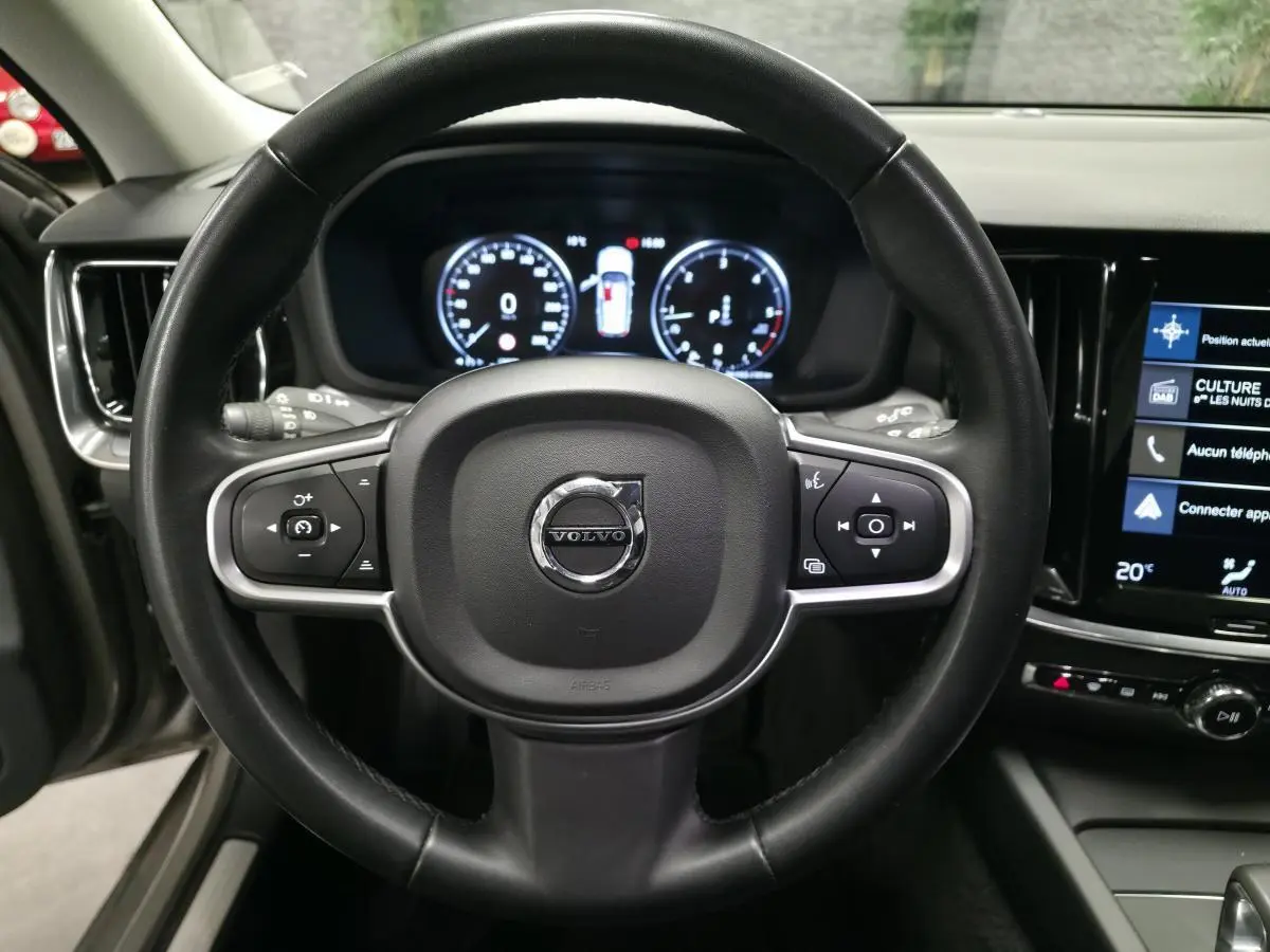 Vue intérieure centrée sur le volant noir de la Volvo V60 2021 avec tableau de bord digital et écran tactile.