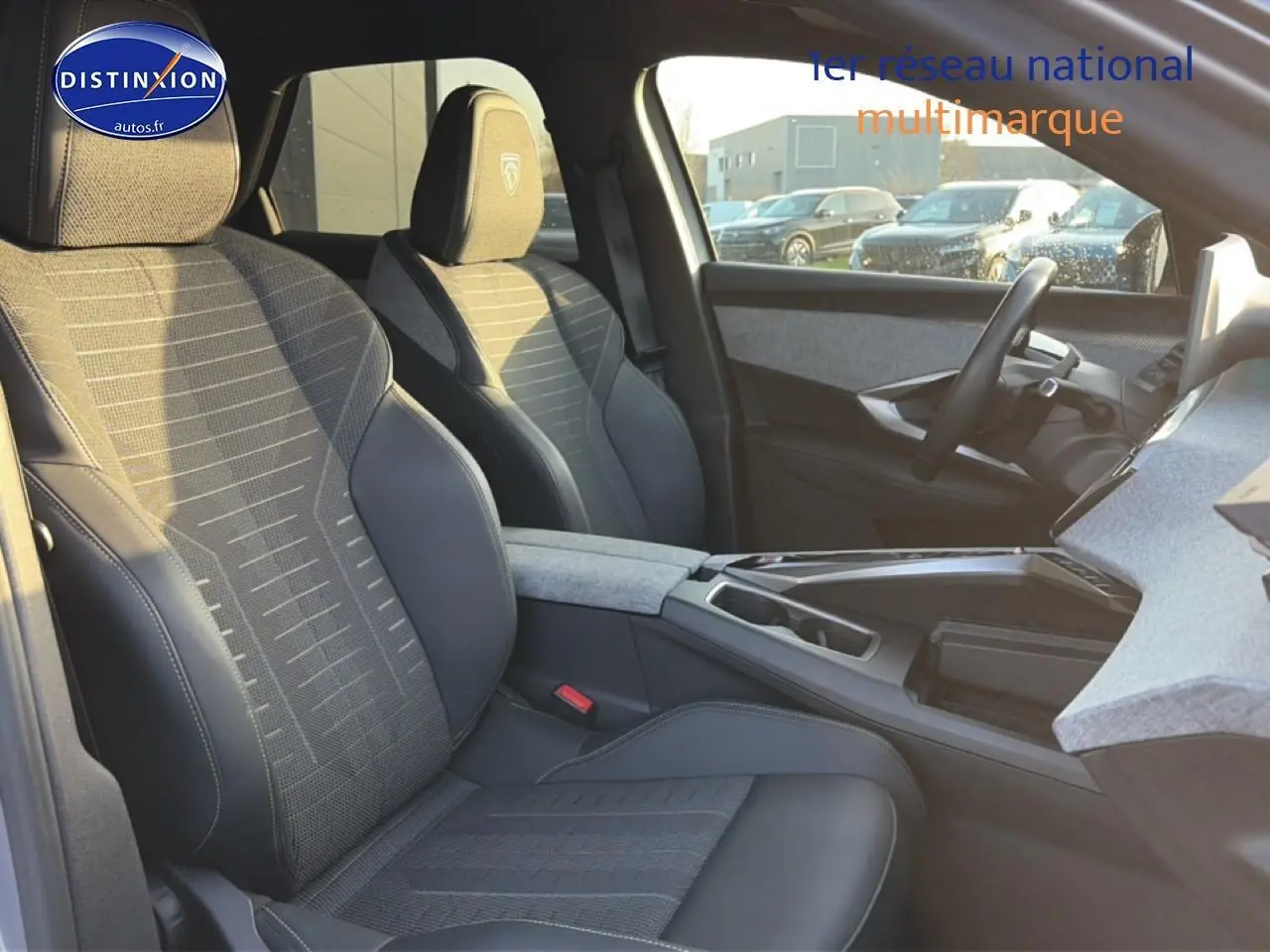 Vue intérieure côté conducteur du Peugeot 3008 gris 2025, sièges tissu et cuir avec accoudoir central.