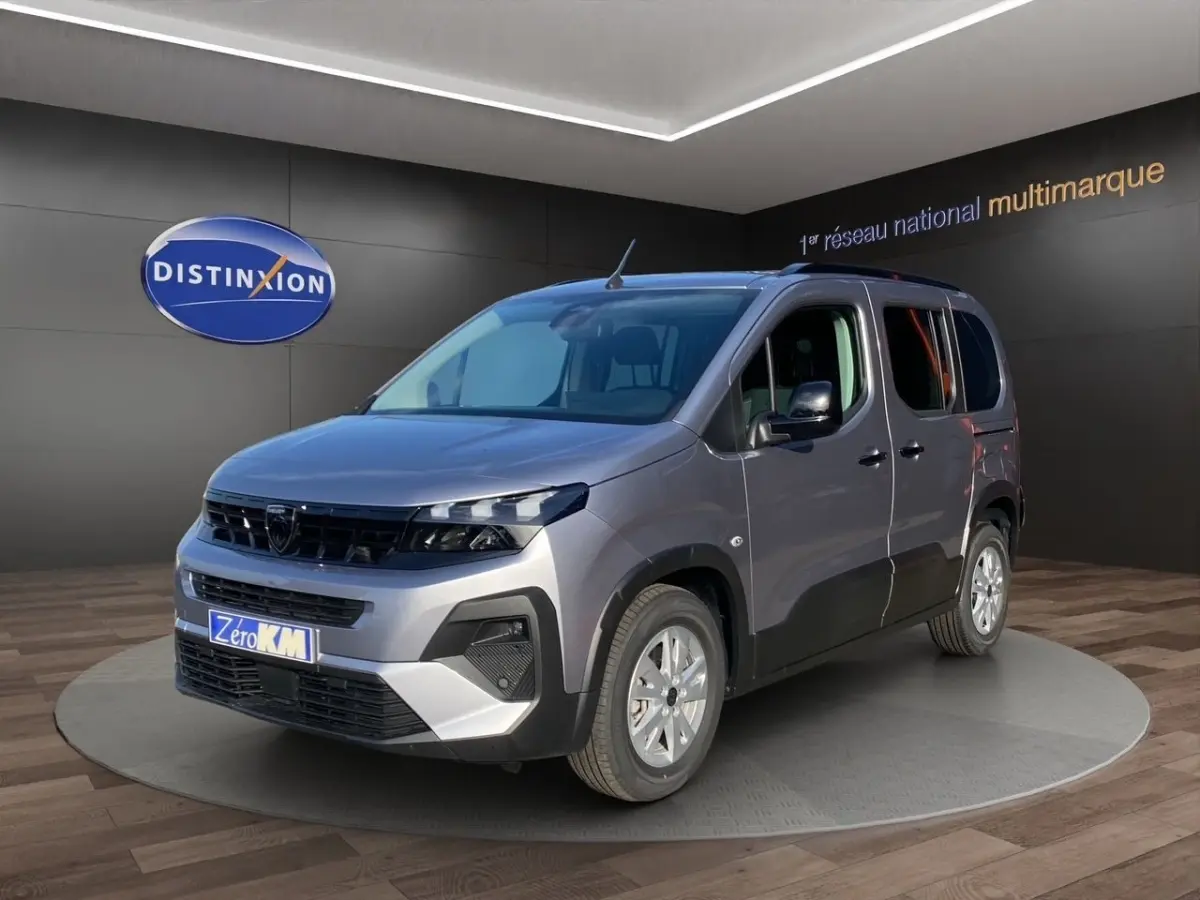 Peugeot Rifter gris clair en 3/4 avant droit, avec calandre noire et jantes argentées en showroom.