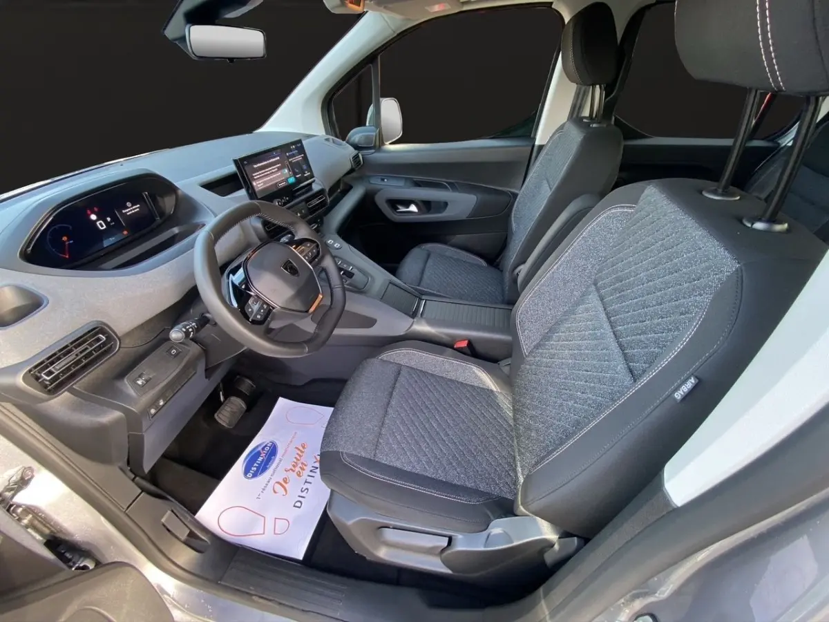 Vue intérieure côté conducteur du Peugeot Rifter gris clair 2026, montrant sièges tissu et tableau de bord digital.
