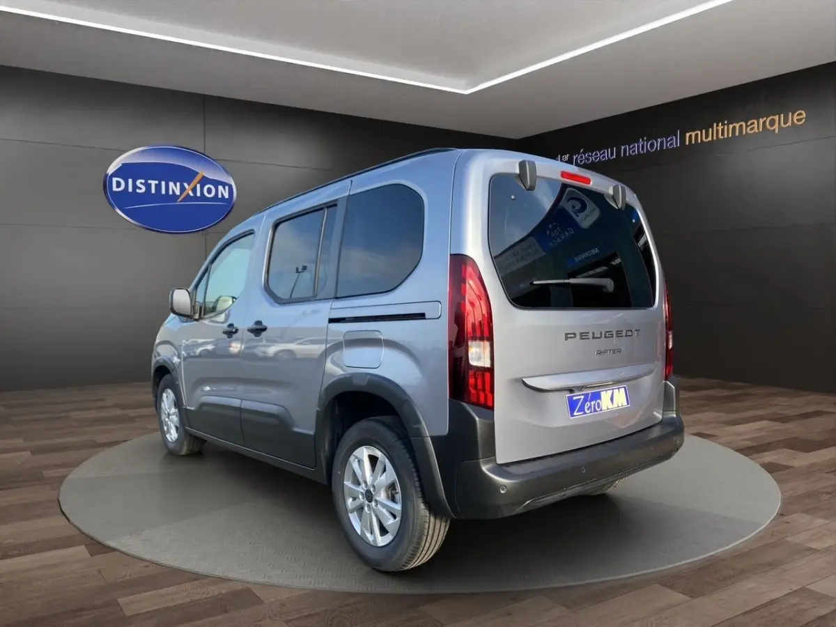 Vue 3/4 arrière droite du Peugeot Rifter gris clair 2026 avec feux arrière verticaux et jantes alliage.