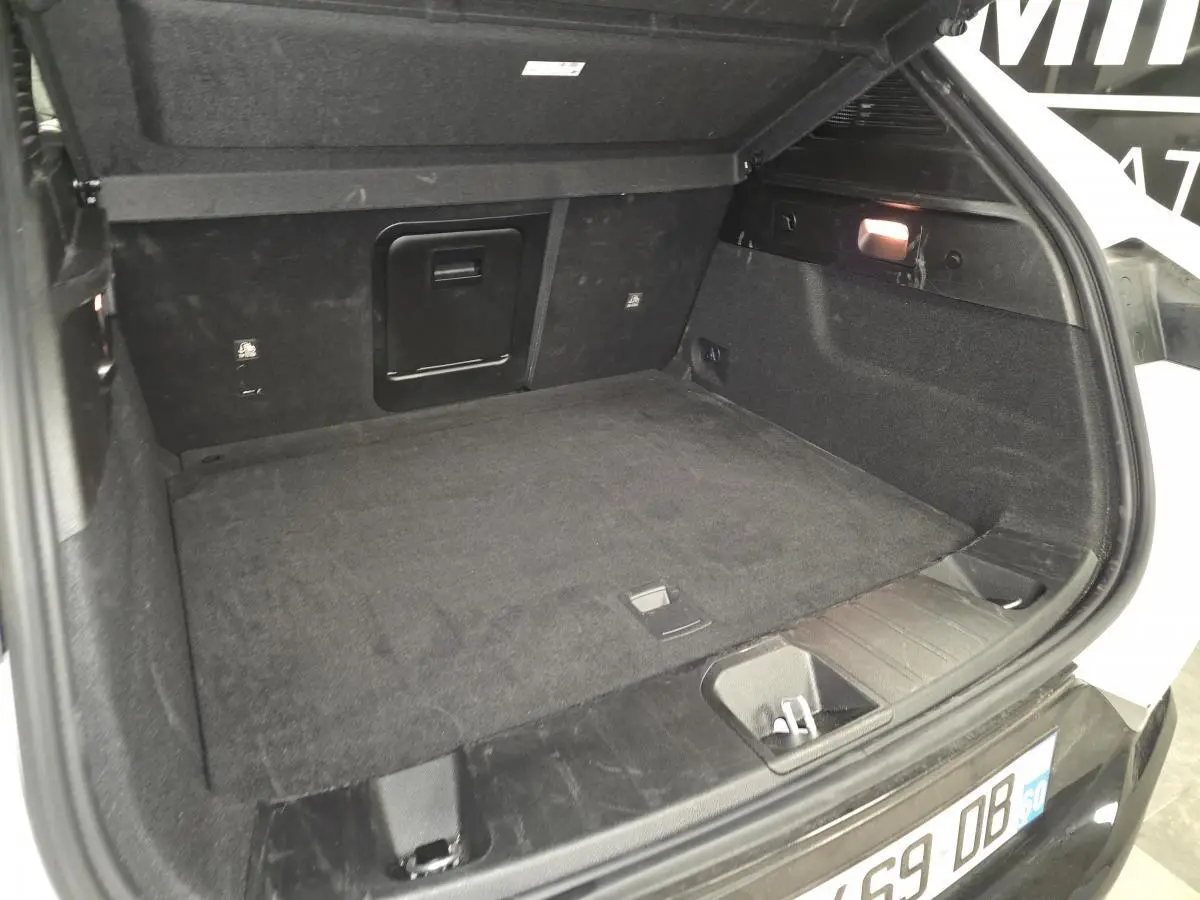 Vue intérieure du coffre ouvert de l'Alfa Romeo Tonale blanc, montrant un espace de chargement propre et bien éclairé.