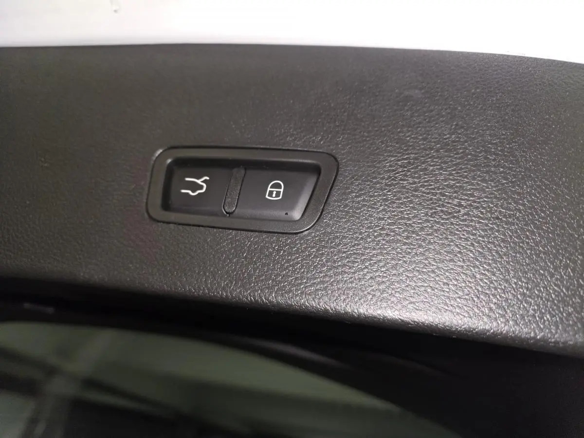 Gros plan sur les boutons d'ouverture du hayon électrique et de verrouillage, sur la garniture intérieure noire.