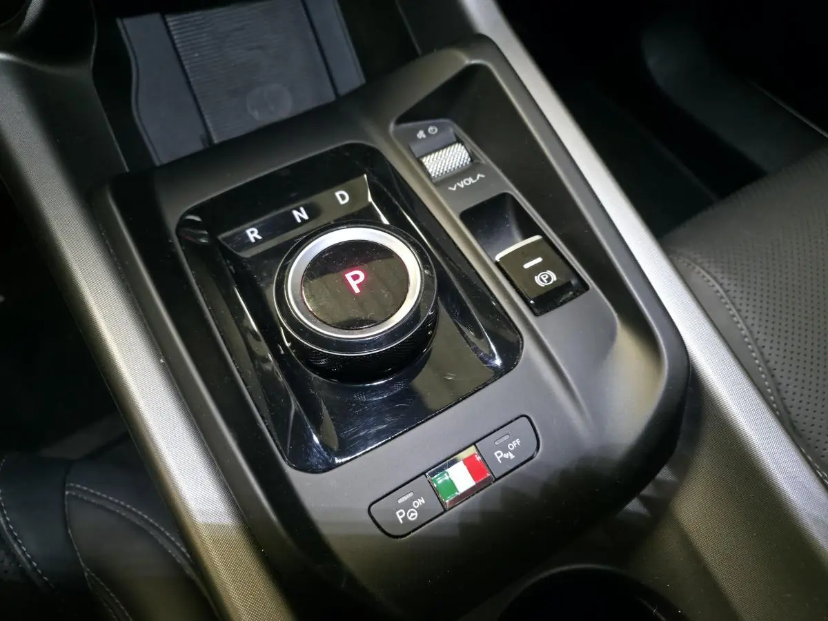 Gros plan sur la molette de boîte automatique et commandes de stationnement de l'Alfa Romeo Tonale blanche, intérieur noir.