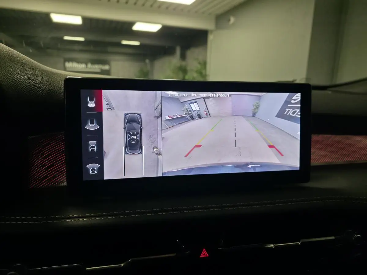 Écran intérieur affichant la caméra 360° de l'Alfa Romeo Tonale blanc, vue arrière en parking intérieur.