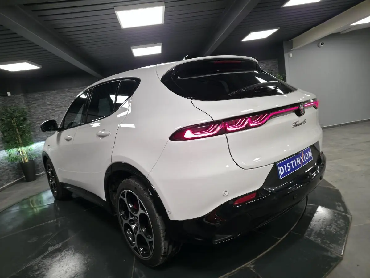 Vue 3/4 arrière droite d'une Alfa Romeo Tonale blanche avec feux arrière LED et jantes alliage noires.
