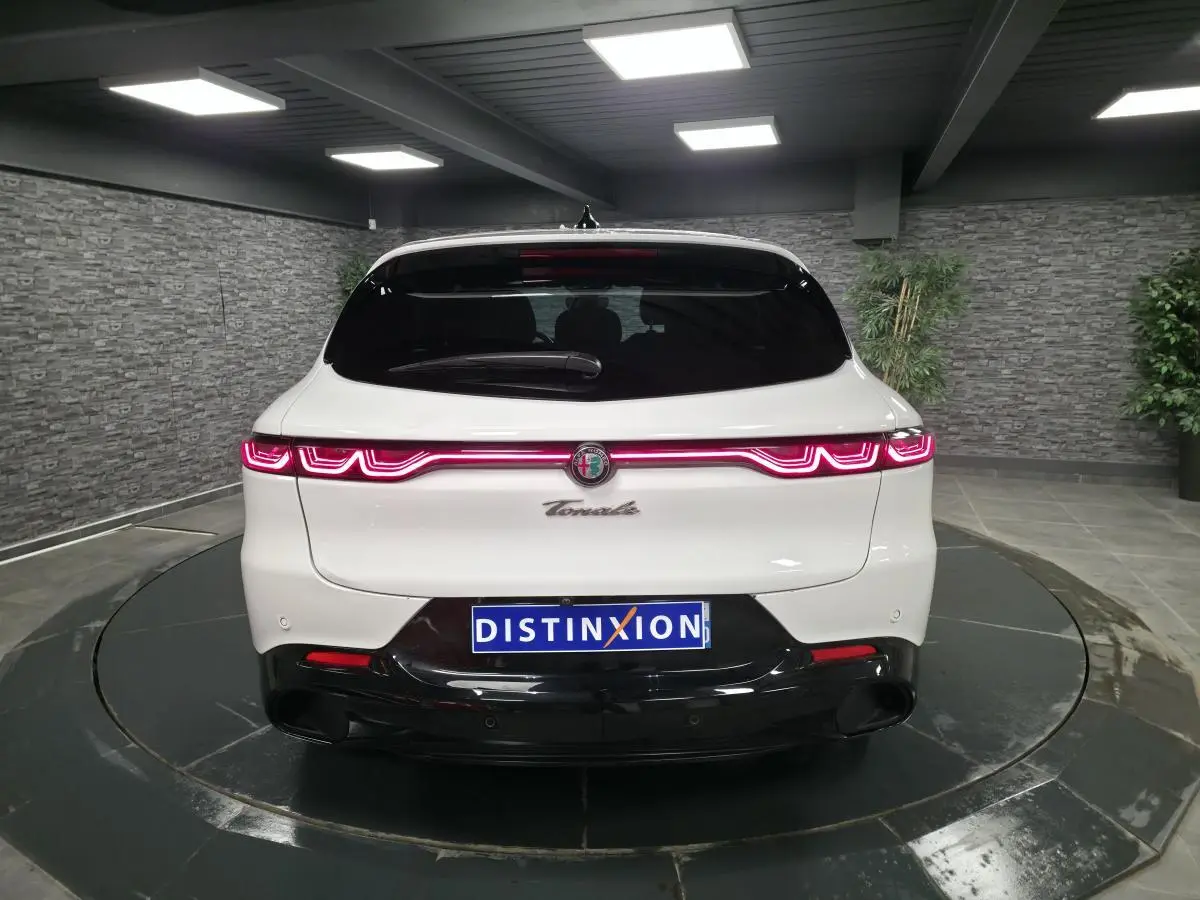 Vue arrière d'une Alfa Romeo Tonale blanche avec feux arrière LED en forme de vague et diffuseur noir brillant.