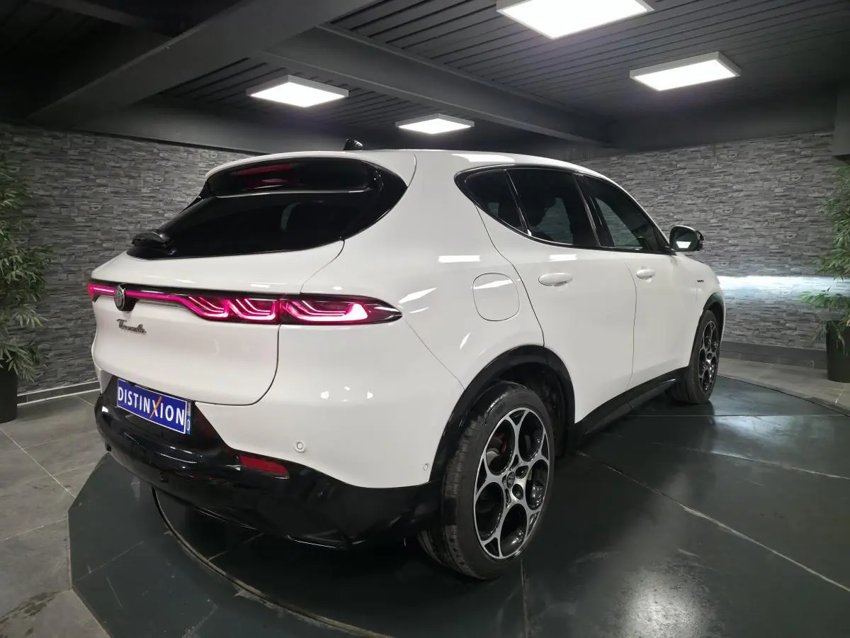 Vue 3/4 arrière droite d'une Alfa Romeo Tonale blanche avec feux arrière LED et jantes alliage noires et argent.