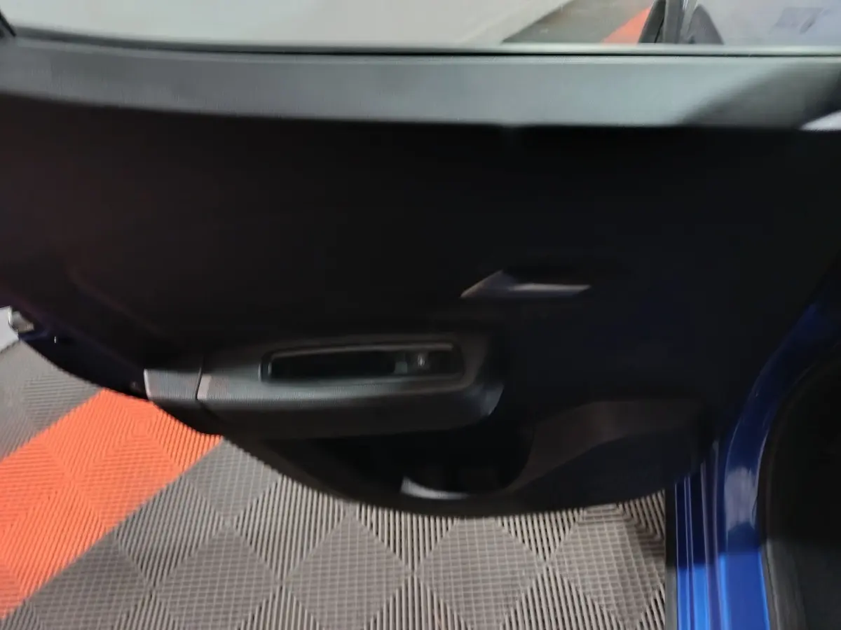 Vue rapprochée de la porte avant gauche bleu foncé de la Dacia Sandero Extreme+ TCe 110 avec poignée intérieure noire.