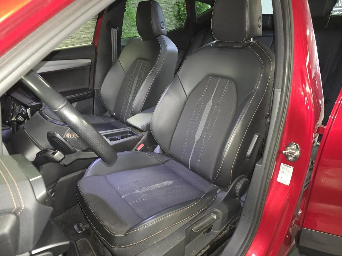 Vue intérieure côté conducteur du CUPRA Formentor rouge 2022, sièges sport noirs avec surpiqûres cuivre.