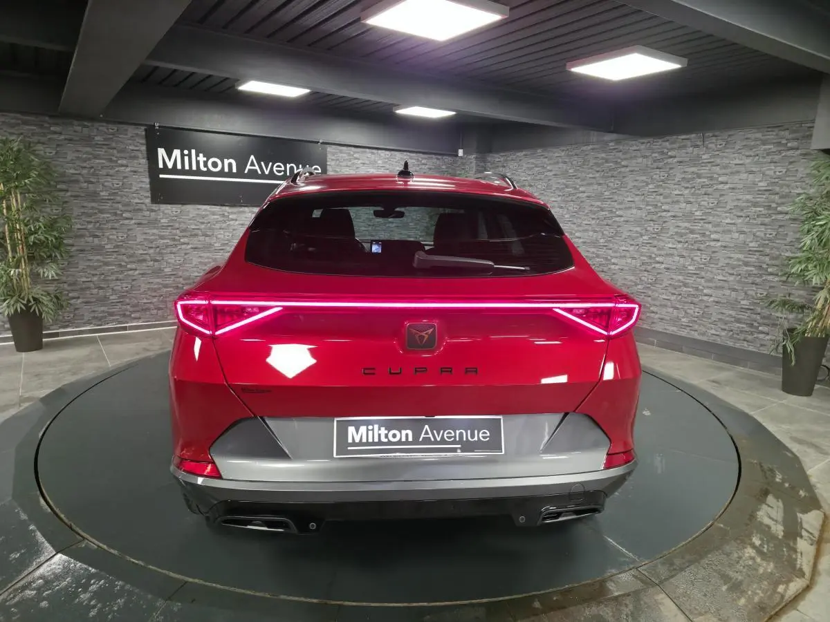 Vue arrière d'une CUPRA Formentor rouge avec bandeau lumineux LED et double sortie d'échappement noire.