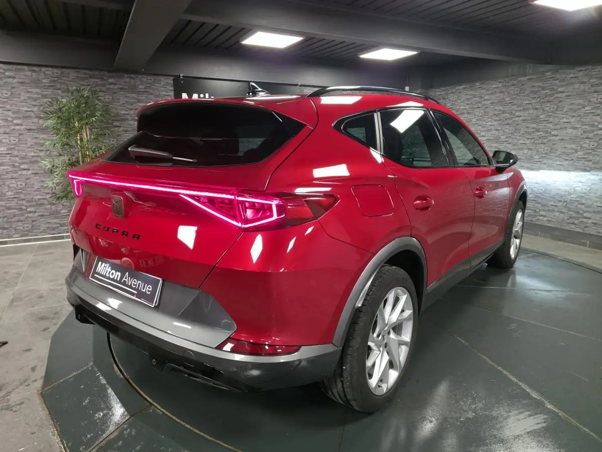 Vue 3/4 arrière droite du CUPRA Formentor rouge avec bandeau lumineux arrière et jantes alliage 18 pouces.