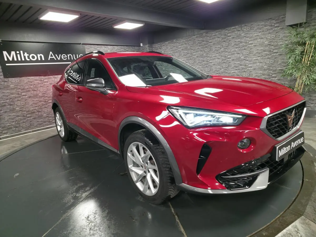 Vue 3/4 avant droite d'une CUPRA Formentor rouge Désir avec projecteurs LED et jantes alliage 18 pouces dans un showroom.