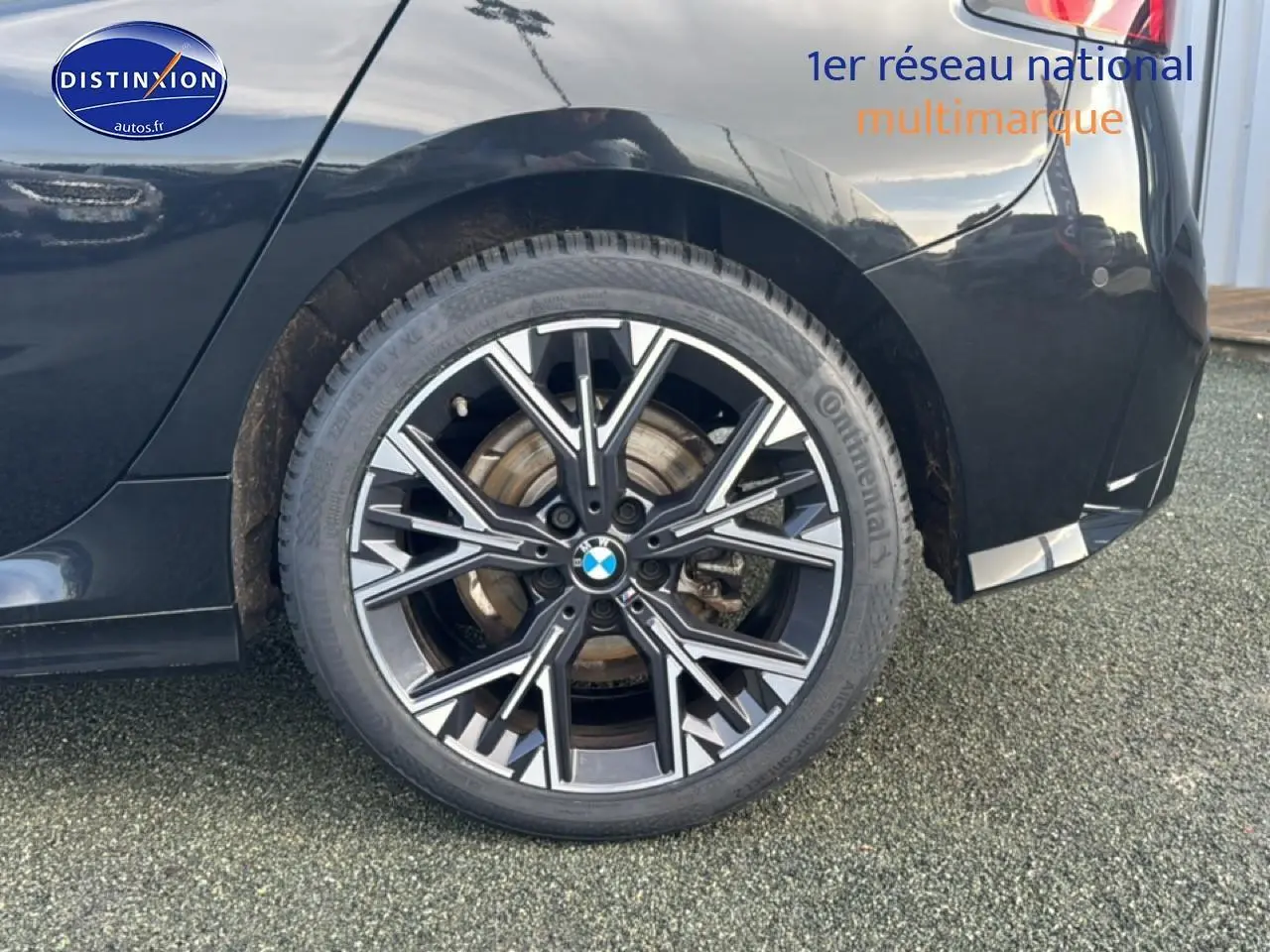 Gros plan sur la roue arrière droite noire d'une BMW Série 1 120da 2024 avec jante alu multibranches.