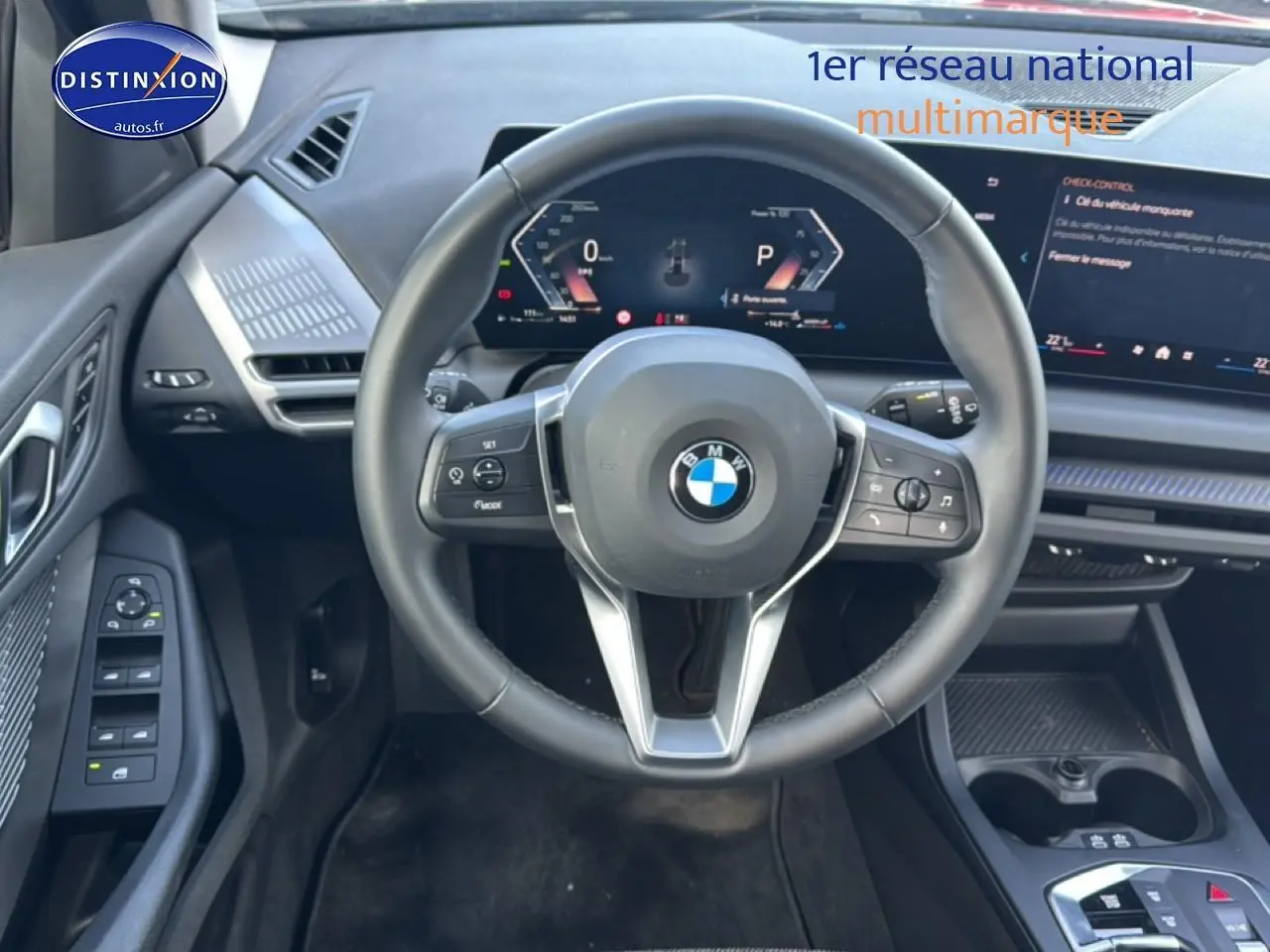 Vue intérieure centrée sur le volant noir multifonction d'une BMW Série 1 120da 2024 avec tableau de bord digital.