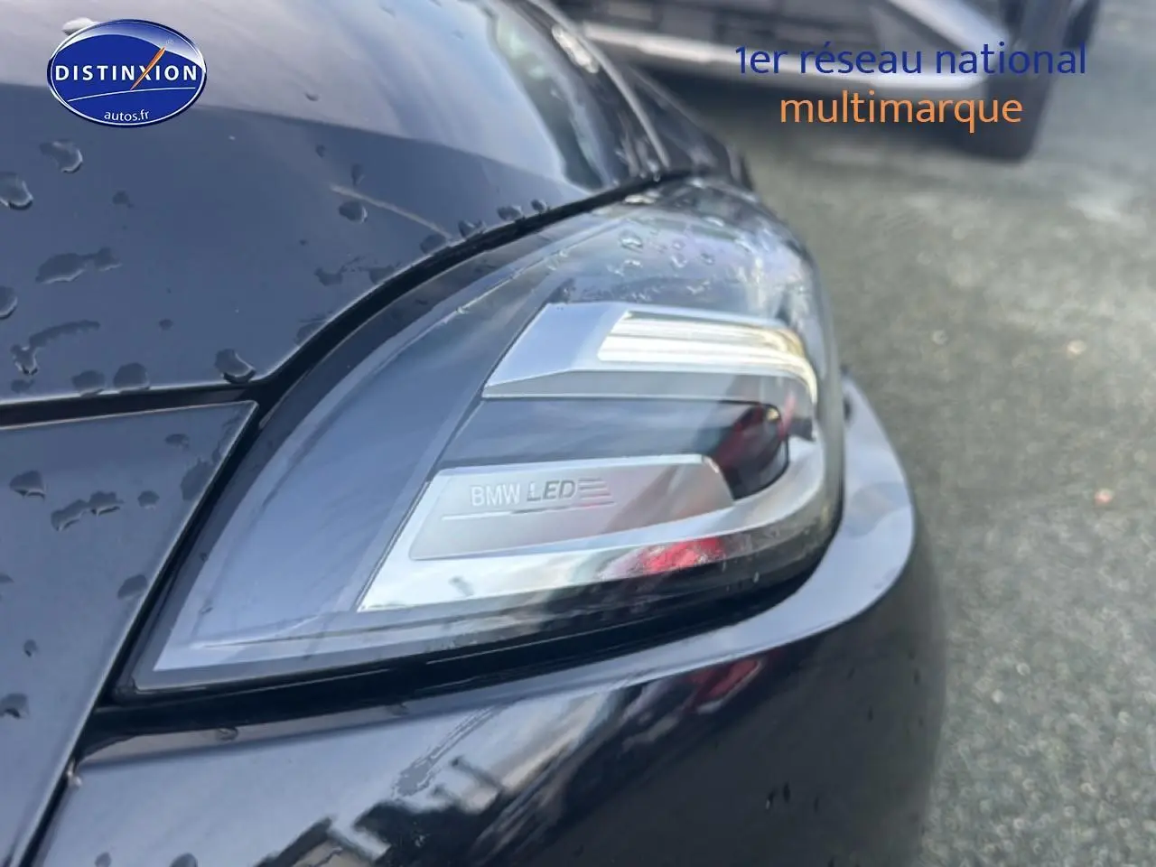 Gros plan sur le phare avant droit LED d’une BMW Série 1 noire (f70) 120da 2024, avec gouttes d’eau visibles.