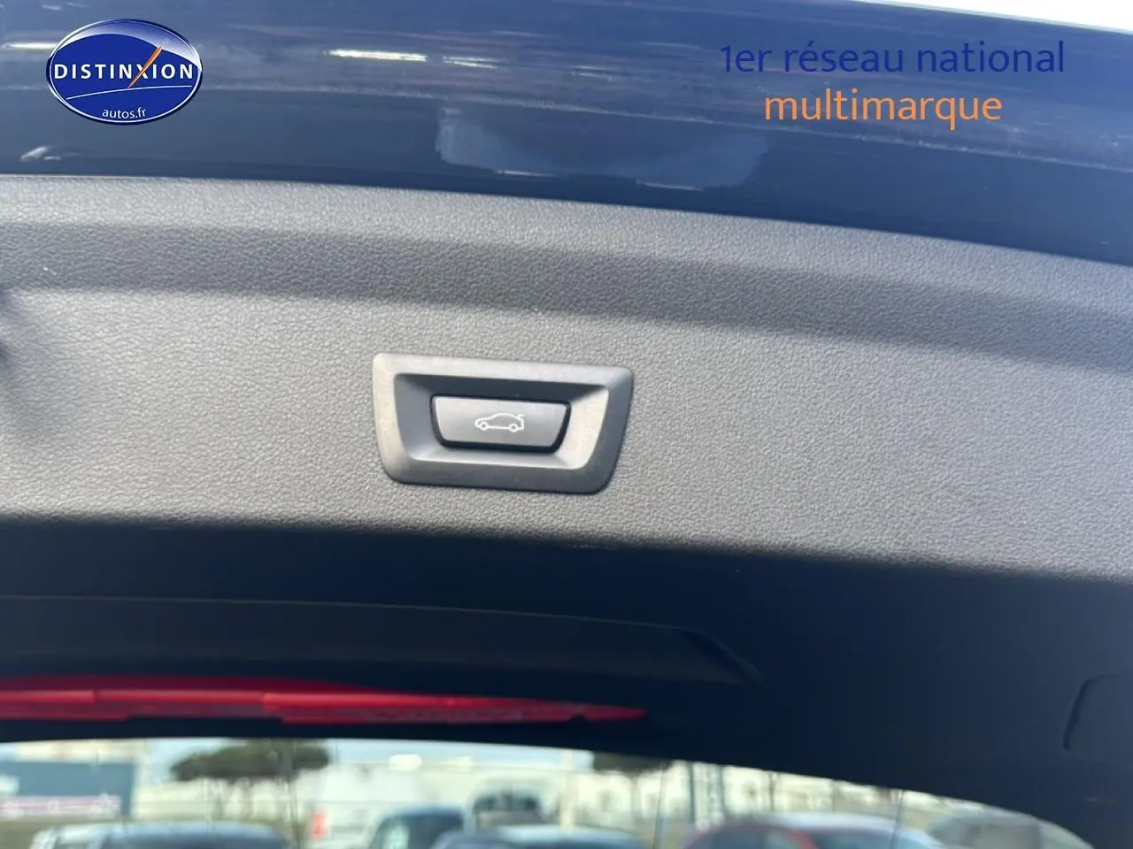Bouton d'ouverture électrique du coffre sur la partie intérieure du hayon d'une BMW Série 1 noire, vue de l'arrière ouvert.