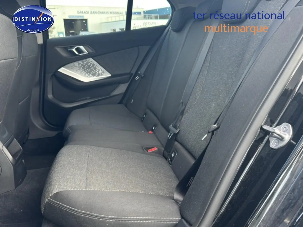 Vue côté droit de la banquette arrière en tissu anthracite dans une BMW Série 1 noire, porte ouverte.