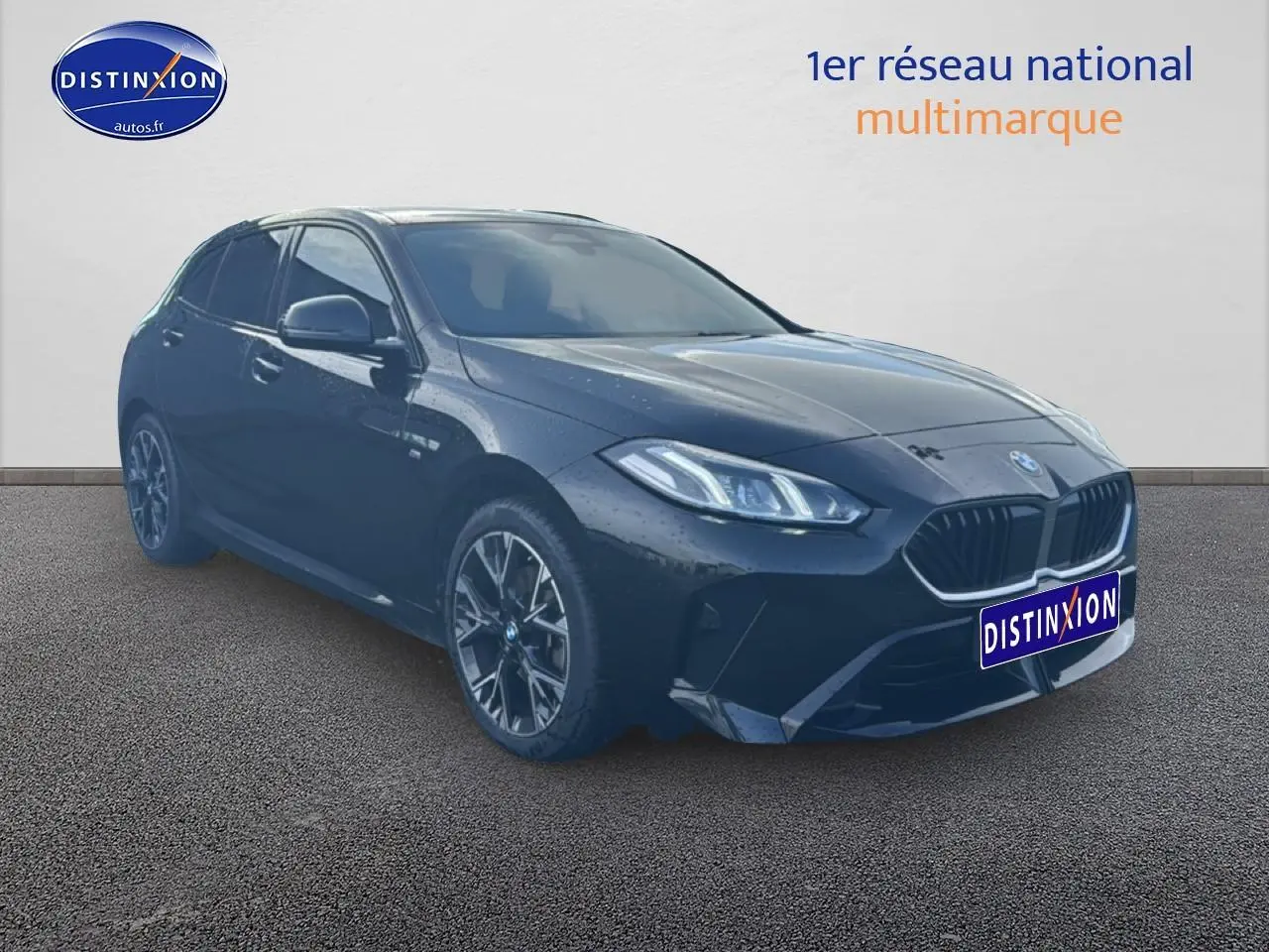 BMW Série 1 noire vue en 3/4 avant droit, avec jantes alliage et phares LED allumés.
