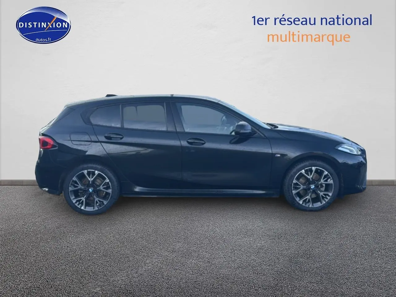 Profil côté gauche d'une BMW Série 1 noire 2024 avec jantes alliage et vitres teintées sur fond neutre.
