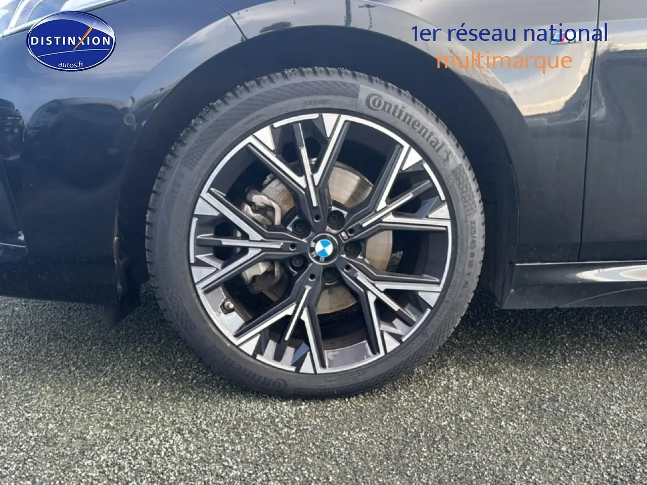 Gros plan sur la roue arrière droite noire d'une BMW Série 1 120da 2024 avec jante alliage multibranches.