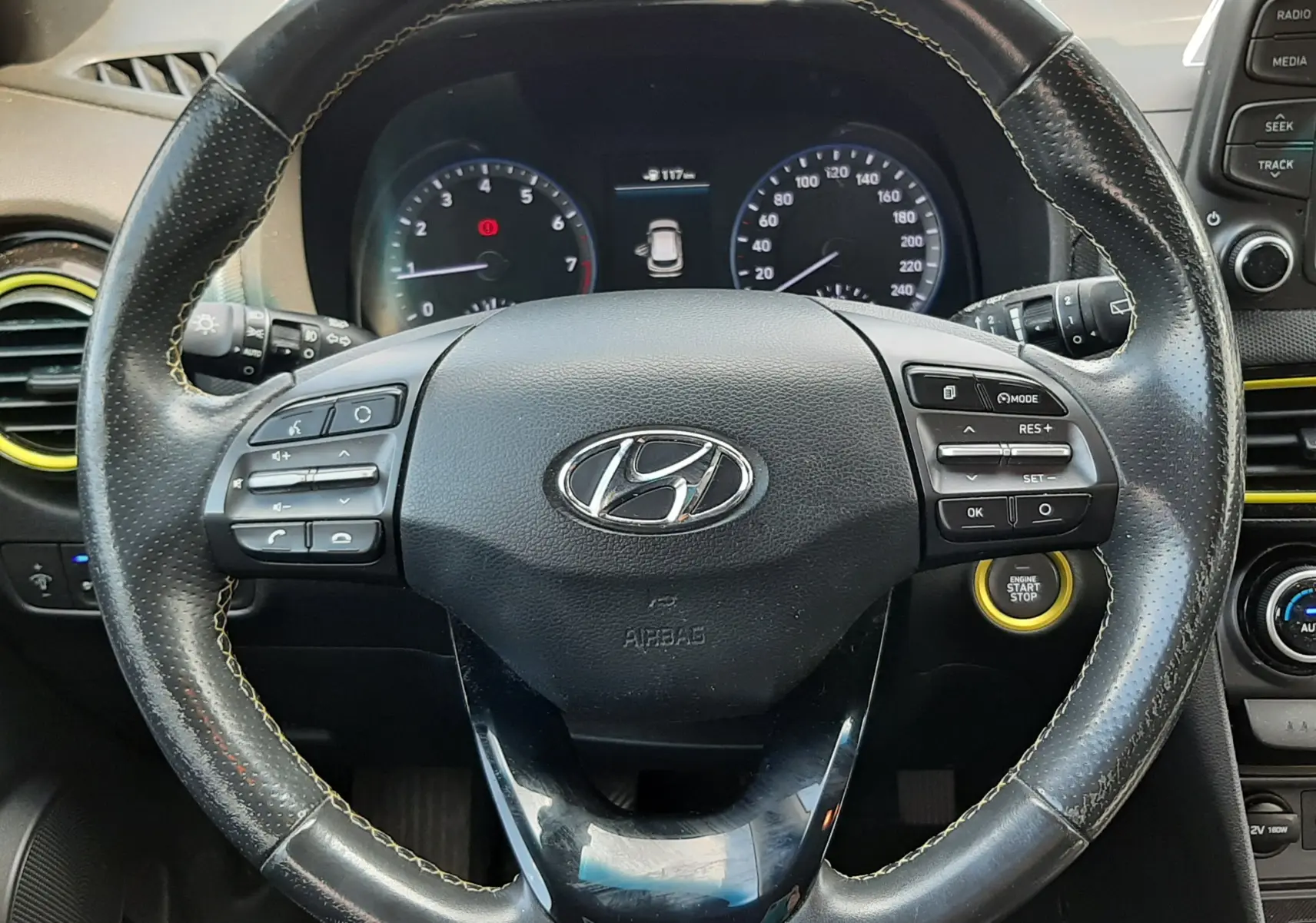 Vue rapprochée du volant en cuir noir du Hyundai Kona 2018, avec commandes intégrées et bouton start/stop visible.