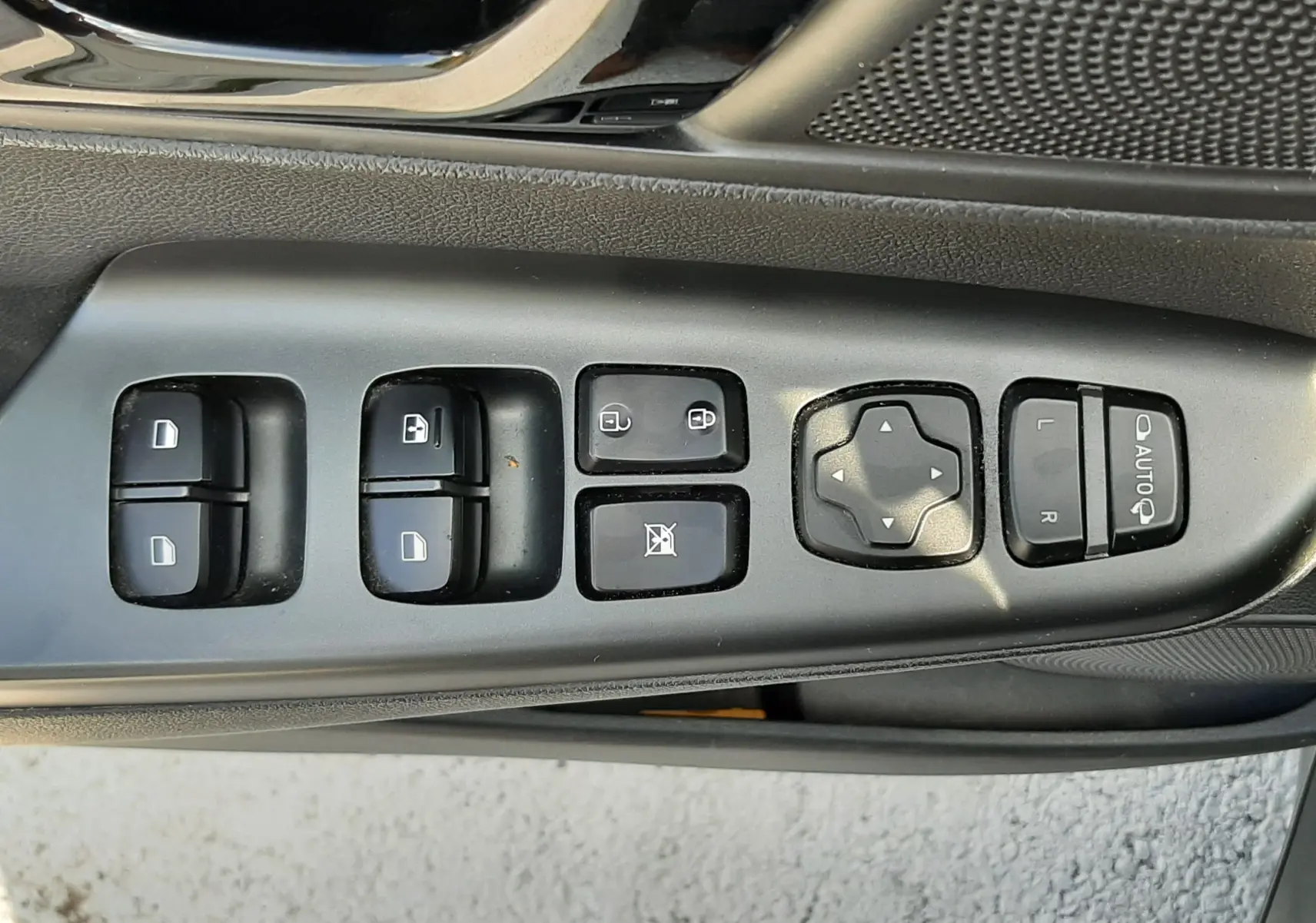 Gros plan sur les commandes de lève-vitres et rétroviseurs côté conducteur d'une Hyundai Kona gris 2018.
