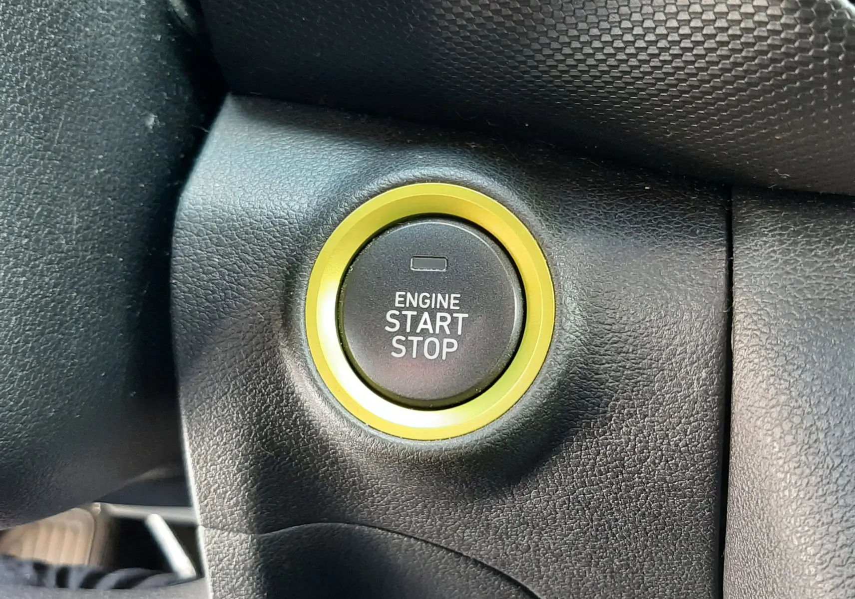 Gros plan sur le bouton start/stop entouré d'un anneau jaune dans l'habitacle noir du Hyundai Kona gris 2018.