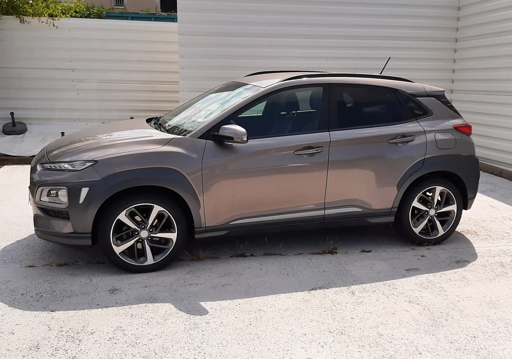 Vue de profil côté gauche d'un Hyundai Kona gris 2018 avec toit noir et jantes alliage bicolores.