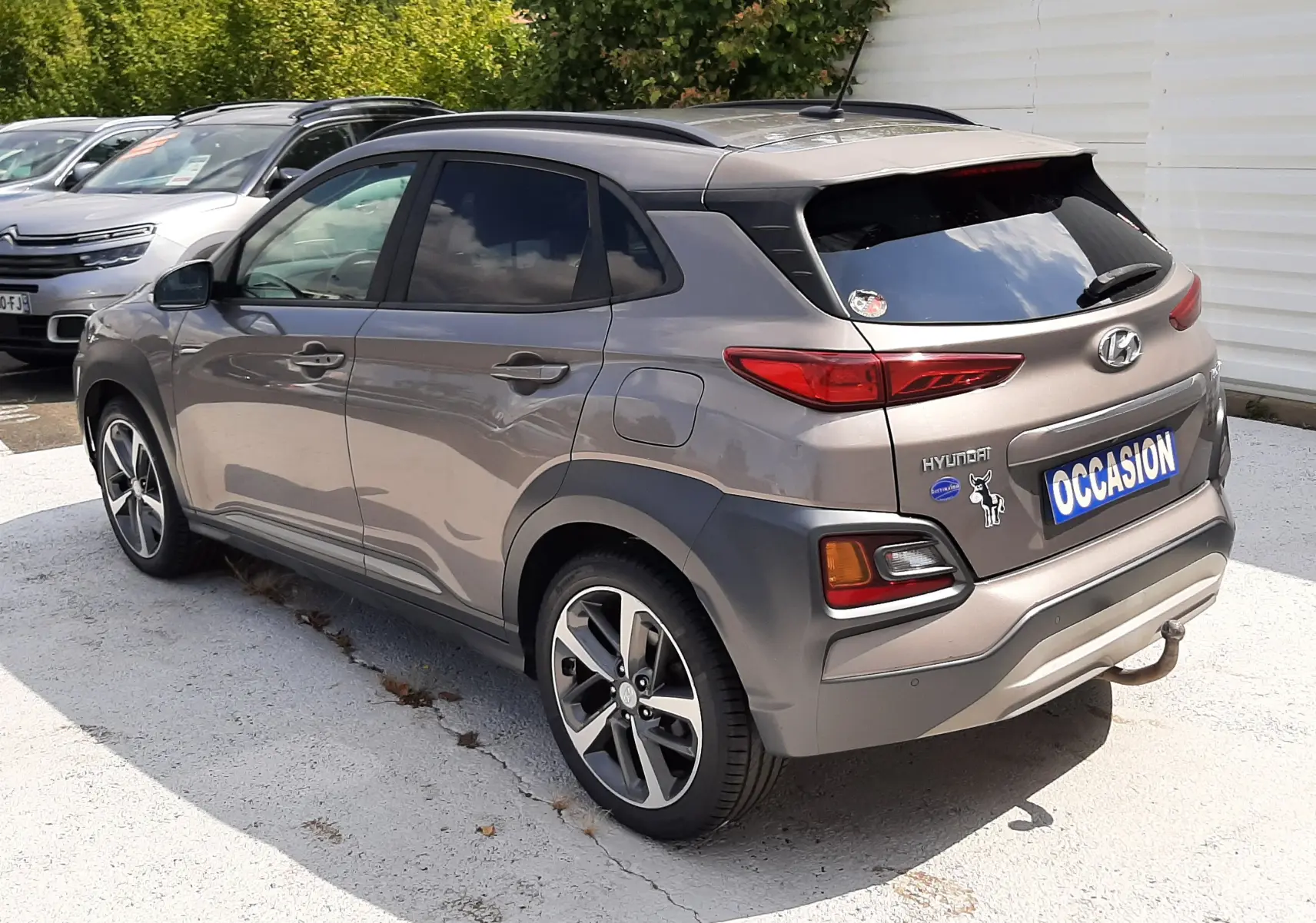 Vue 3/4 arrière droite d'un Hyundai Kona gris 2018 avec jantes bi-ton et stickers sur le hayon.