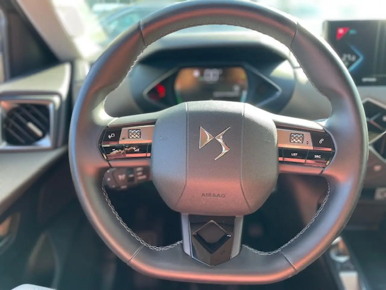 Vue rapprochée du volant cuir noir du DS3 Crossback E-Tense 2021 avec commandes intégrées et logo DS central.