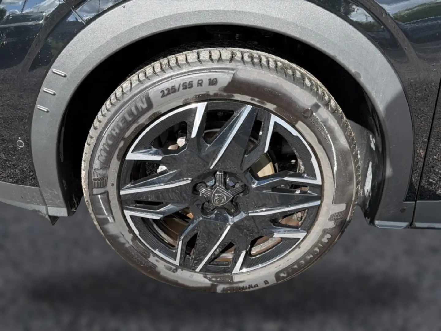 Gros plan sur la roue avant gauche noire d’un Peugeot 3008 1.2 hybrid 145 allure e-dcs6 avec jante alu bicolore.